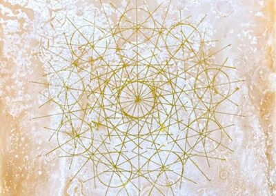 Geometric golden lines form an intricate, symmetrical mandala pattern on a textured, light beige and white background. The design appears delicate and radiates outward in a circular formation.