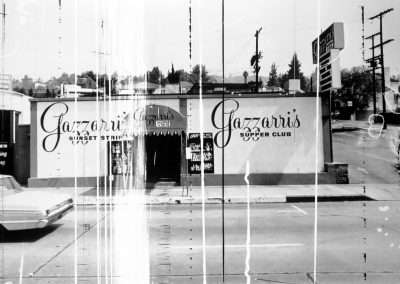 Black and white photo of Gazzarri's nightclub on Sunset Strip, featuring a vintage car parked outside and signs advertising "Gazzarri's supper club". The image, captured by Ed Ruscha, has vertical fold marks.