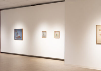 A bright art gallery features five colorful paintings of surreal floral arrangements by McConville Munroe, each framed and evenly spaced on a white wall. The floor is light wood, and the open, minimalist space captures a fresh 2025 vibe.