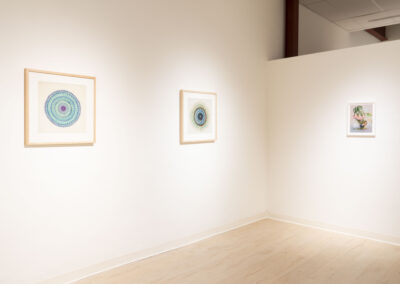 A gallery wall displays three framed artworks: two geometric, circular mandalas on the left and a smaller botanical illustration by McConville on the right, all set against a crisp white background. Perfect for a fresh 2025 look.