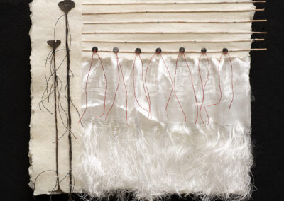 A textured artwork with a handmade paper background highlights the Art of ReUse, featuring vertical lines of string and plant stems on the left, six horizontal sticks at the top, flowing white fibers, sheer fabric, and red threads hanging down on the right.