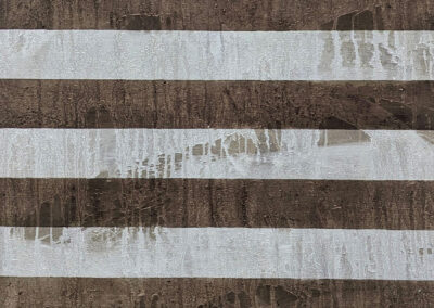 Brown and white horizontal stripes with streaks and smudges of a translucent, textured substance partially covering the surface, creating an abstract, uneven pattern.